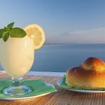 Sicilian lemon granita and a typical warm brioche with blue sea and Mount etna in the background